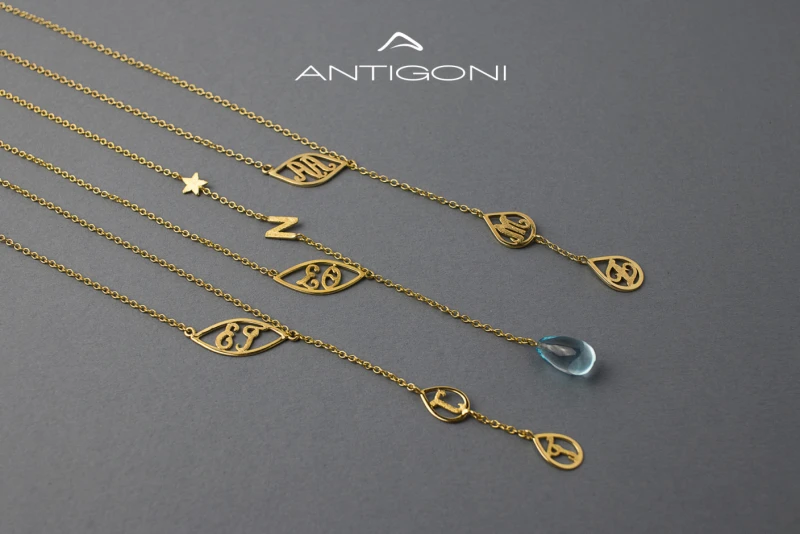 Elaborate gold necklace which consists of different gold teardrop-shaped patterns within which various letters corresponding to initials of names are designed