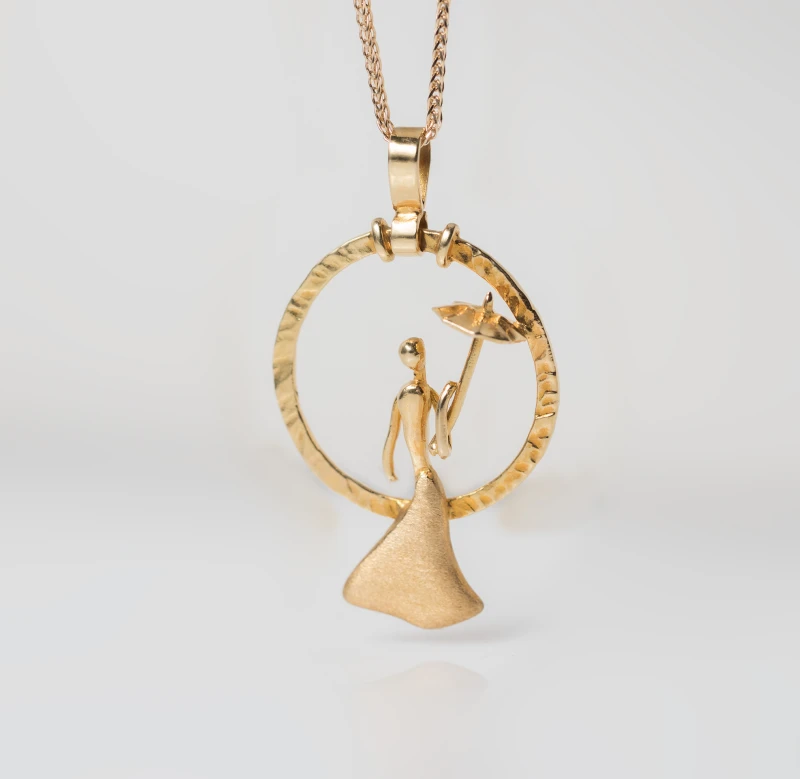 Gold pendant with a gold chain while the elegant round design depicts a female figure