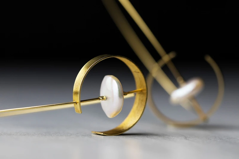 Long gold pendant earrings in an elegant drop shape decorated with round flat pearls