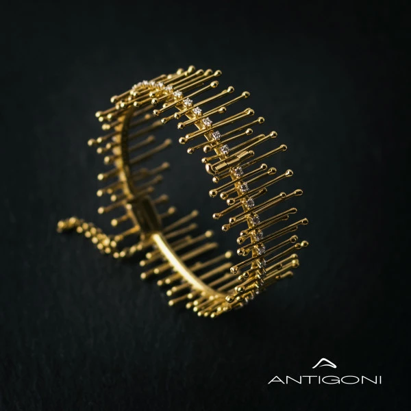 Gold bracelet decorated with diamonds and striking long vertical designs that end in small spheres. The bracelet is made of solid yellow gold